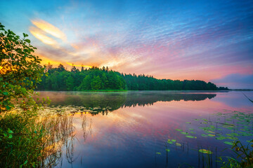 Beautiful landscape with colorful sunsrise over forest lake