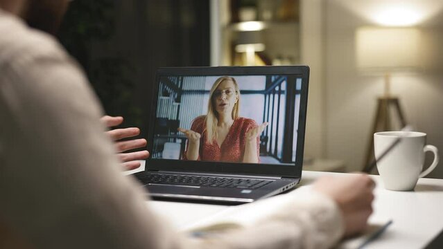 Young caucasian student having remote lesson, looking at laptop screen and having discussion with felame teacher
