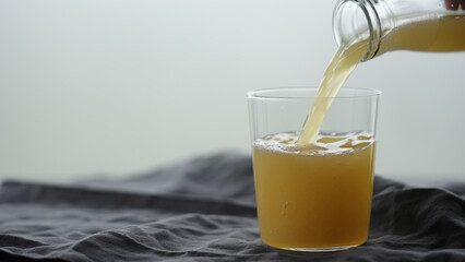 pour orange soft drink into tumbler glass on linen cloth