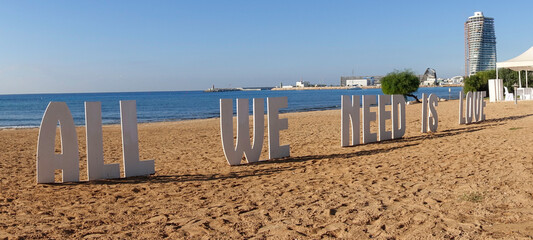 All We Need is Love sign on a Mediterranean beach - obrazy, fototapety, plakaty
