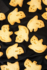 Baked butter cookies in ghost shapes formed by cookies cutter on black Halloween sweet treats - 538693401
