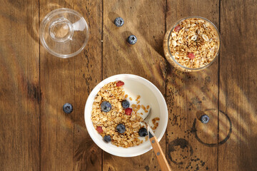 granola with yogurt and berries in a white bowl on a wooden table