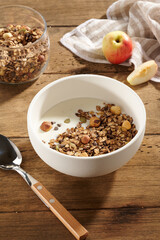 granola with yogurt and berries in a white bowl on a wooden table