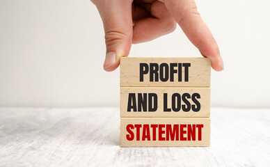 Business photo shows profit and loss statement words on wooden blocks and hand