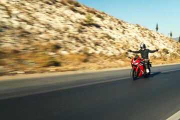 Side view of a motorcycle rider riding red race motorcycle on the highway with motion blur.