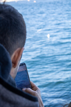 A person trying to take a photo with a phone is a person taking a sea photo. Selective Focus.