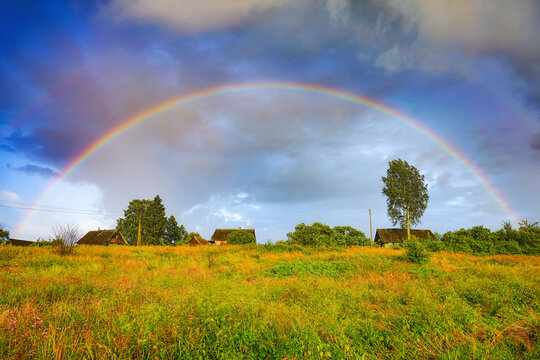 Rainbow over stormy sky. Rural landscape with rainbow over dark stormy sky in a countryside at summer evening.