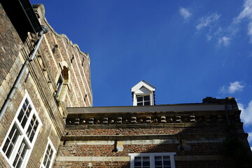 Alte Gebäude mit sanierten Fassaden aus braunem Backstein vor blauem Himmel im Sonnenschein in der...