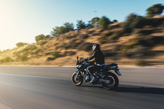Side view of a motorcycle rider riding on the highway with motion blur.