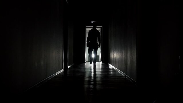 Slow motion, a strange man walks along the corridor of an office or hotel. backlight, a mysterious silhouette goes to the camera. High quality FullHD footage