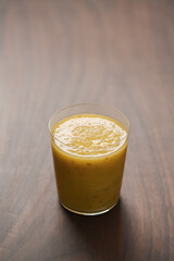 Mango lulo smoothie on walnut wood table with copy space