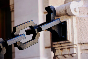 heavy black steel chain link closeupof square sections attached to textured stone pier. soft...