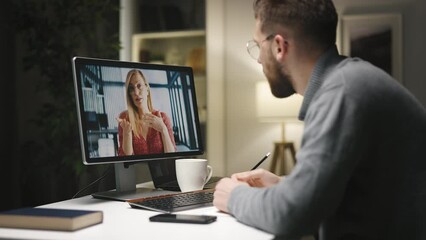 Young caucasian male in eyeglasses having videochat with felmale and making notes, preparing a project.