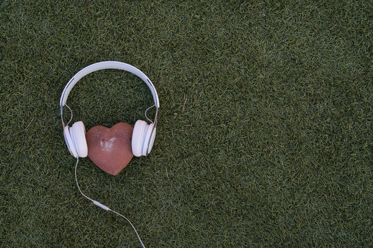 stone hearts with headphones on grass background - Powered by Adobe