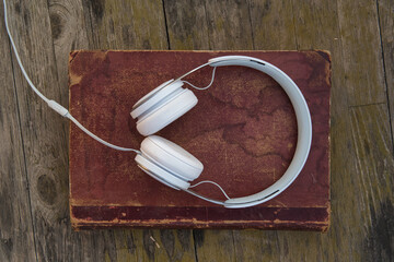 headphones on old book and wooden background
