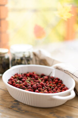 Dried rose hips on the windowsill against the backdrop of an autumn landscape