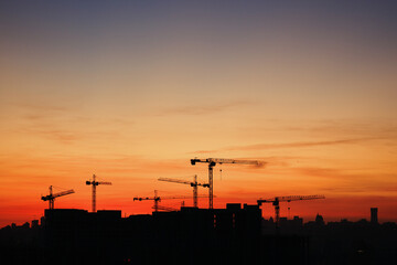 Fototapeta na wymiar Silhouette of construction cranes at sunset.
