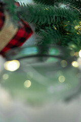 Close-up of a green glass and a candle, a sprig of a Christmas tree and a gift in a red checkered package. Photo out of focus. People with poor eyesight, farsightedness.