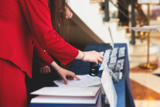 Process of checking in on a conference congress forum event, registration desk table, visitors and attendees receiving a name badge and entrance wristband bracelet and register electronic ticket