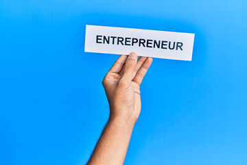 Hand of caucasian man holding paper with entrepreneur word over isolated blue background