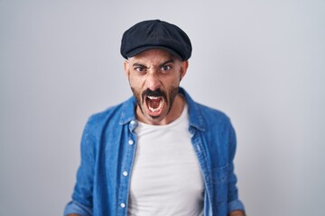 Hispanic man with beard standing over isolated background angry and mad screaming frustrated and...
