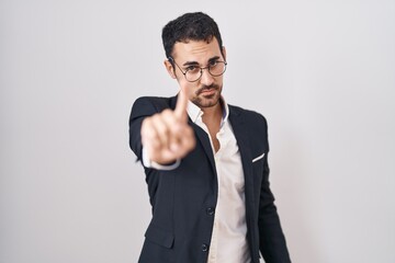 Handsome business hispanic man standing over white background pointing with finger up and angry expression, showing no gesture