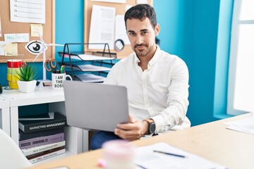 Young hispanic man business worker using laptop working at office
