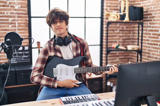 Young hispanic man musician playing electrical guitar at music studio