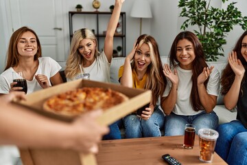 Group of young friends woman surprise for italian pizza sitting on the sofa at home.