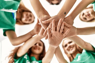 Group of young volunteers woman smiling happy with hands together at charity center.