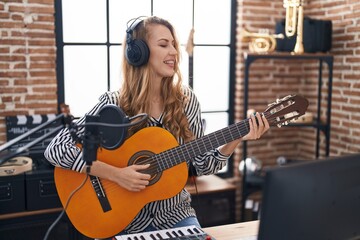Young blonde woman musician playing classical guitar at music studio