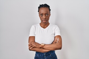 Beautiful black woman standing over isolated background skeptic and nervous, disapproving...
