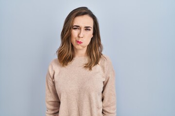 Young woman standing over isolated background puffing cheeks with funny face. mouth inflated with air, crazy expression.
