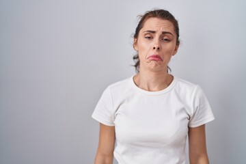 Beautiful brunette woman standing over isolated background depressed and worry for distress, crying angry and afraid. sad expression.