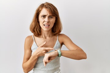 Beautiful caucasian woman standing over isolated background in hurry pointing to watch time,...