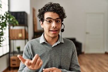 Young hispanic call center agent man smiling happy working at the office.