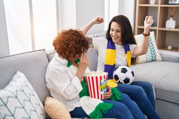 Two women mother and daughter supporting soccer match at home