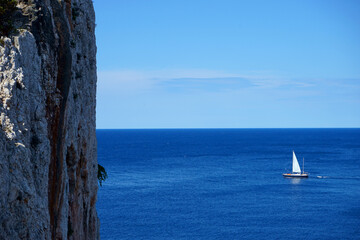 sailboat beyond steep cliff