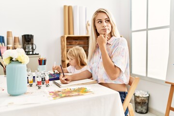 Caucasian family of mother and daughter painting at art studio serious face thinking about question...