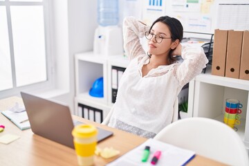 Young hispanic woman business worker relaxed with hands on head at office