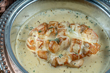 Chicken fillet in creamy sauce with garlic, in cast  pan on dark background with thick gravy.