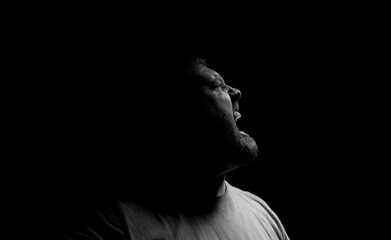Screaming angry man on a dark background.