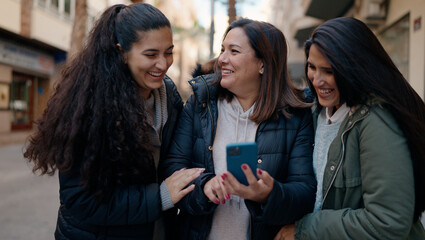 Mother and daugthers using smartphone standing together at street