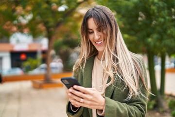 Young woman smiling confident using smartphone at park