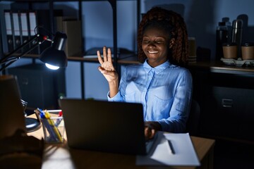 African woman working at the office at night showing and pointing up with fingers number three while smiling confident and happy.