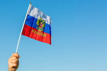 Female hand holding flag of Russia against blue sky