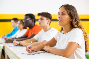 Girl studying in taxi driving school, sitting at his desk with group of people.