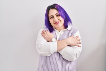 Plus size woman wit purple hair standing over white background hugging oneself happy and positive, smiling confident. self love and self care