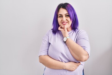 Plus size woman wit purple hair standing over isolated background looking confident at the camera...