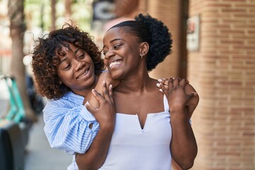 African american women mother and daughter hugging each other at street